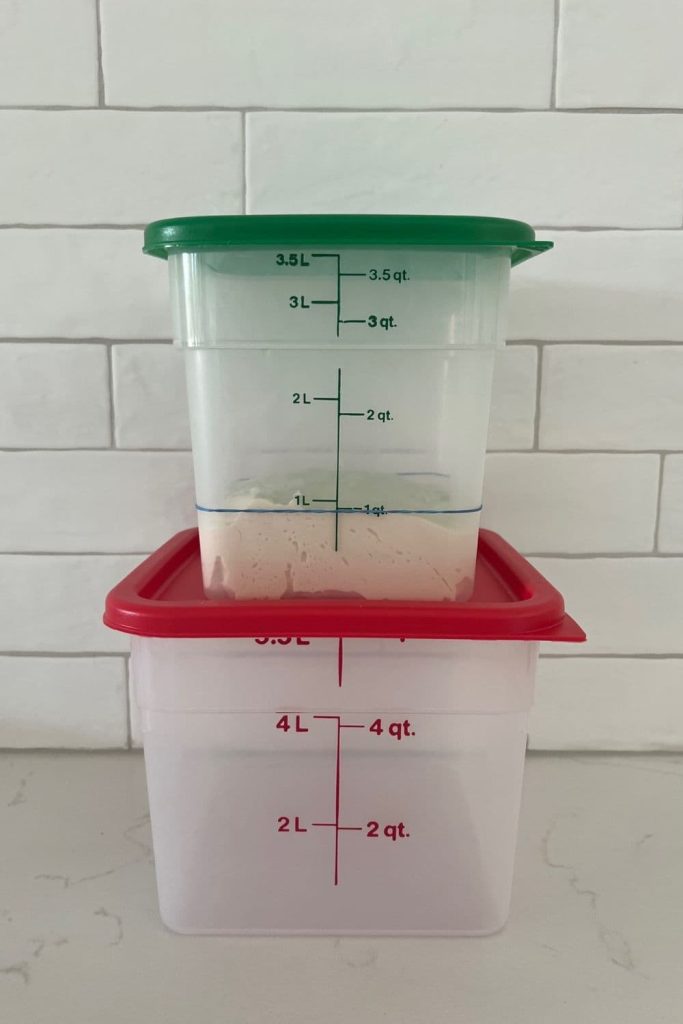 A green lidded Cambro Container sitting on top of a red lidded Cambro Container.