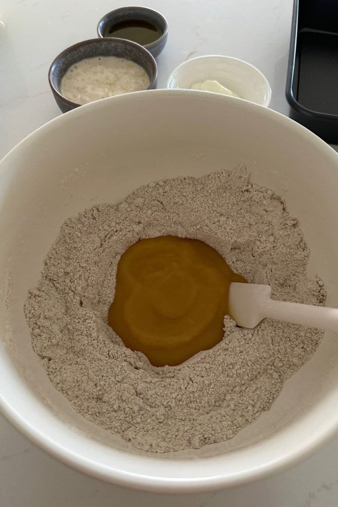 All of the dry ingredients mixed in a bowl, with a well in the centre to add the wet ingredients for this sourdough applesauce cake.