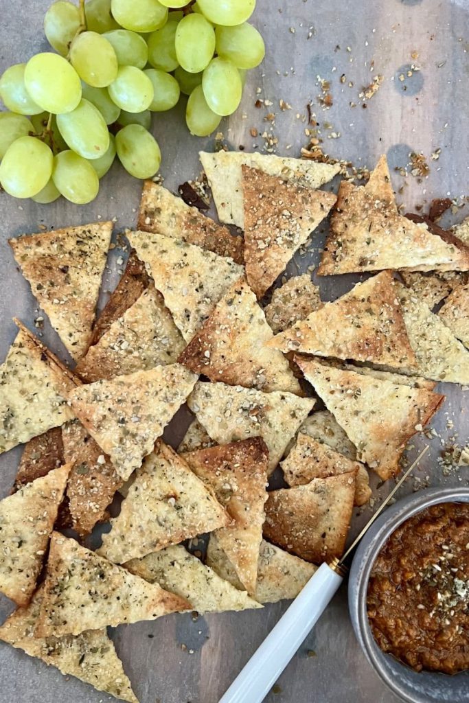 sourdough crackers served on a platter with green grapes and olive dip.