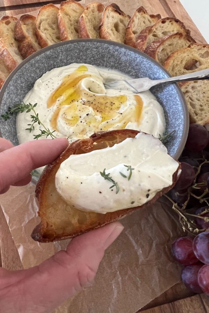 Whipped ricotta dip that has been spread onto a sourdough crostini.