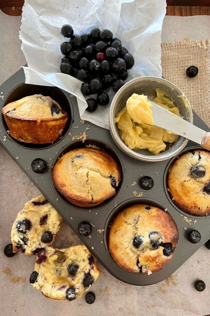 Overnight blueberry sourdough muffins sitting in a 6 hole muffin tray.