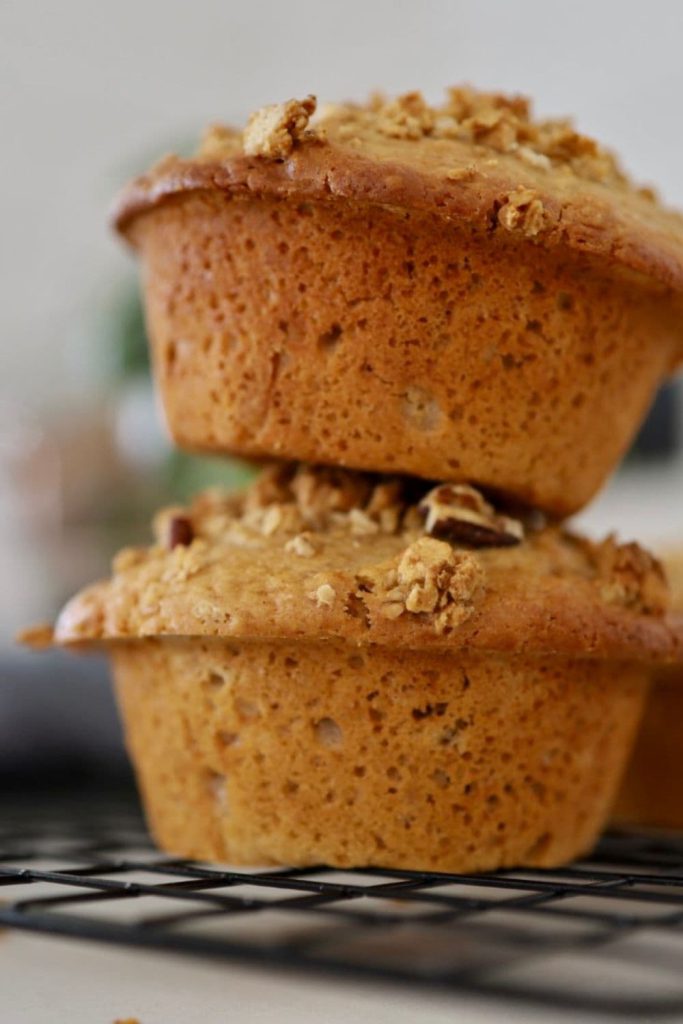 2 jumbo sourdough granola muffins stacked on top of each other. They are sitting on a black wire cooling rack.