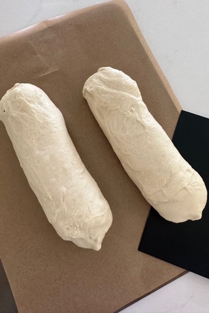 Transferring the shaped French Bread dough onto a parchment lined tray.