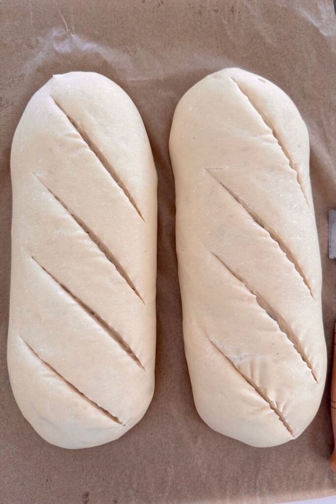 Two loaves of sourdough French Bread that have been slashed with a lame.