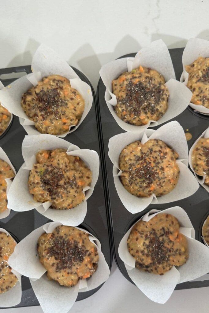 6 sourdough morning glory muffins that have not yet been baked. You can see the seed mixture that has been placed on top.