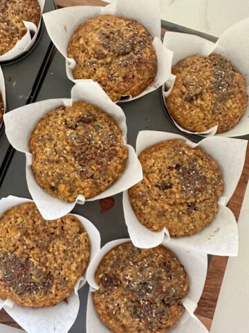 Sourdough Morning Glory Muffins in paper liners sitting in a 6 hole muffin tray.