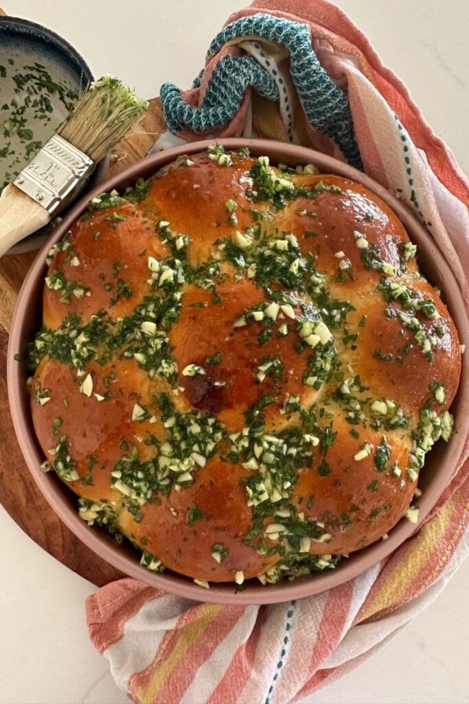 Sourdough Pampushky that have been brushed with a generous amount of herb and garlic oil. There is a pastry brush sitting at the back of the tin.