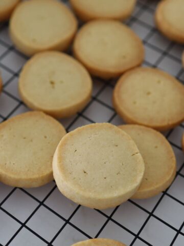 Sourdough shortbread cookies on a black wire cooling rack.