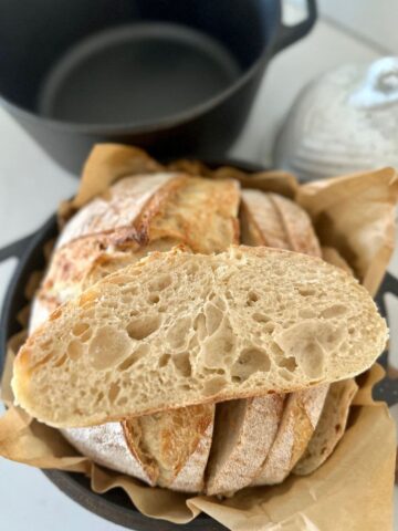 Sourdough Bread made with all purpose flour. There is a slice of all purpose sourdough bread sitting on the top of the whole loaf.