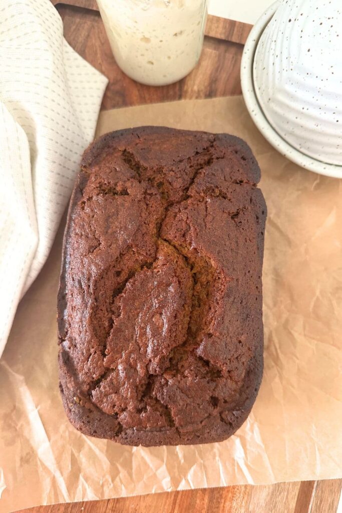 Whole loaf of sourdough discard quick bread laid on a sheet of parchment paper.