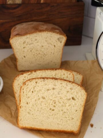 Sourdough Farmhouse White Sandwich loaf cut into slices and displayed on a piece of parchment paper.