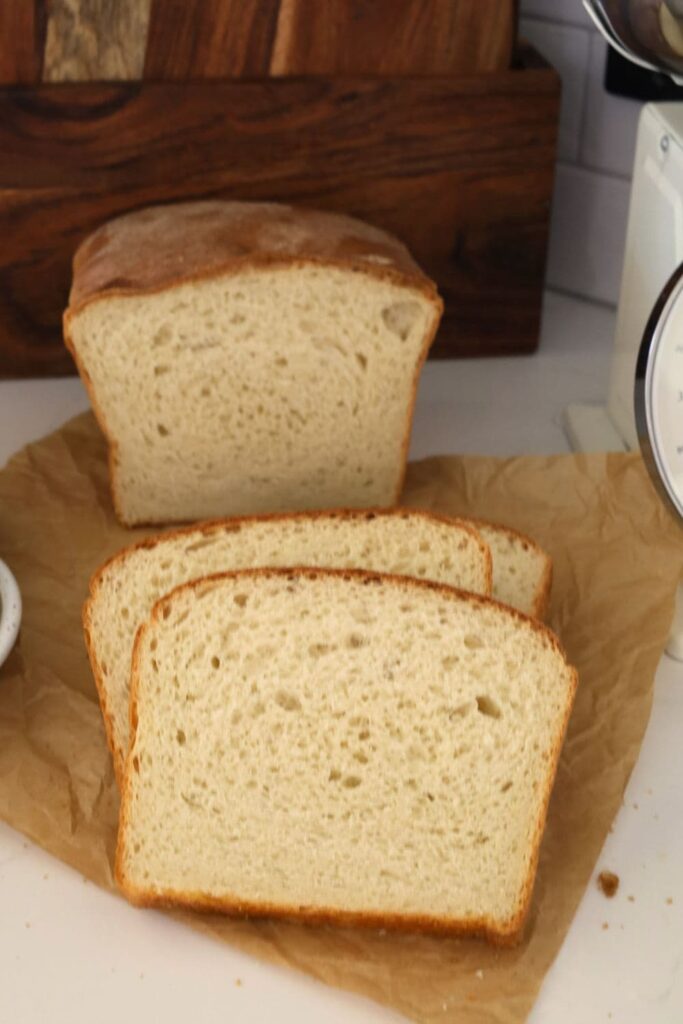 Sourdough Farmhouse White Sandwich loaf cut into slices and displayed on a piece of parchment paper.