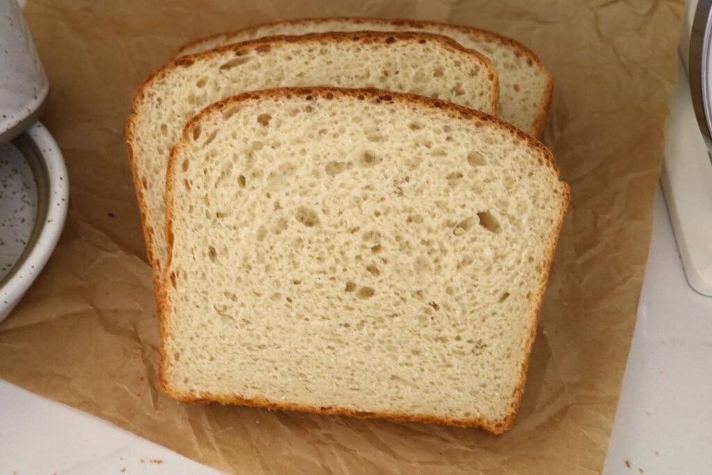 3 slices of sourdough farmhouse white sandwich bread displayed on a slice of parchment paper.