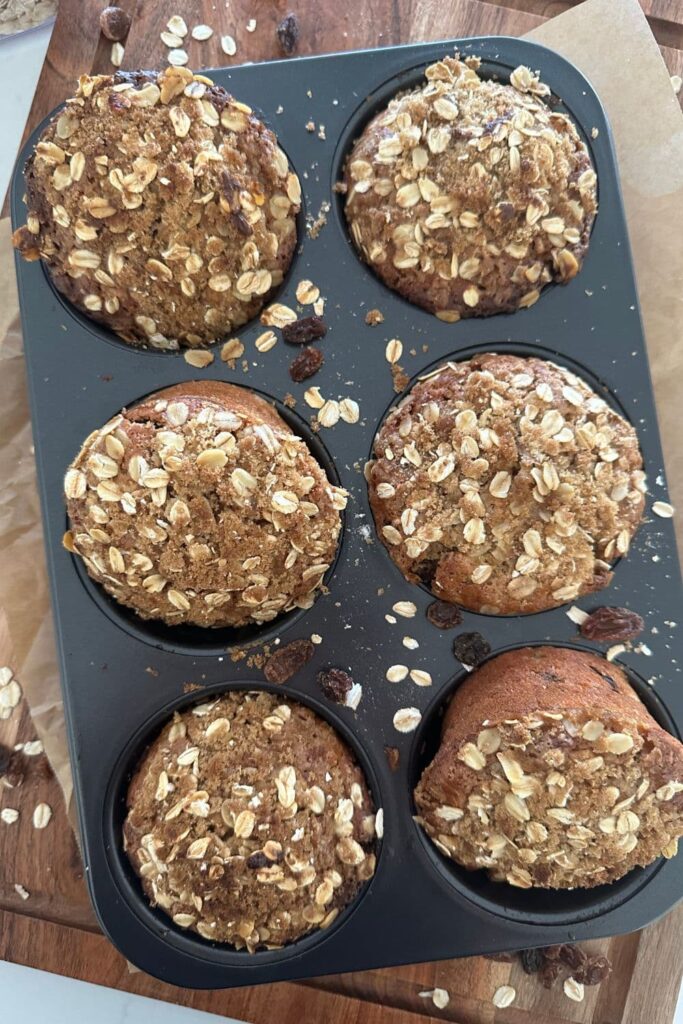 6 sourdough oatmeal raisin muffins sitting in a muffin tin They have just come out of the oven.