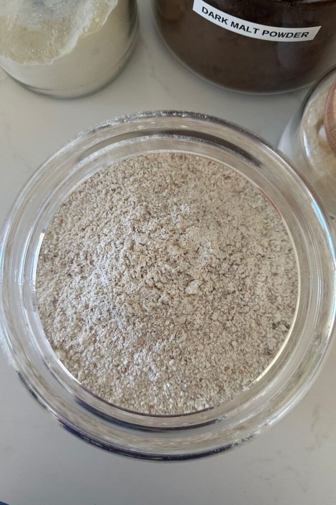 Jar of dark malt powder photographed from above.