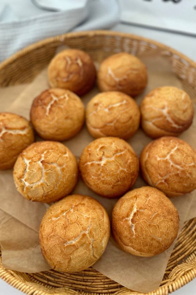 A basket lined with parchment paper containing around 10 sourdough tiger rolls.