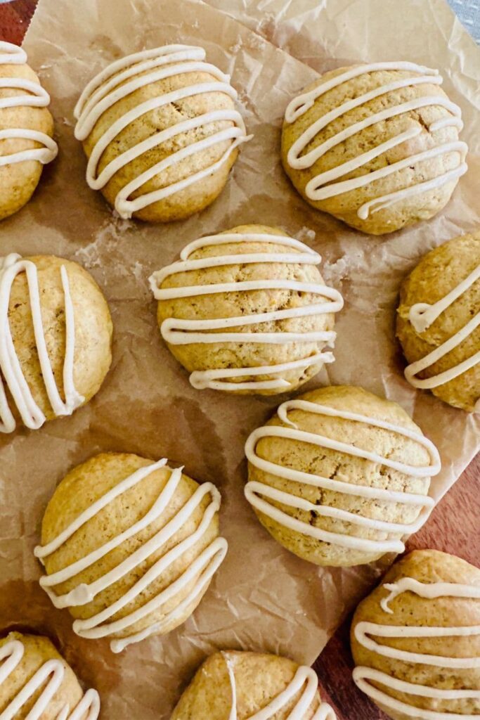 Sourdough pumpkin spice cookies with maple glaze laid out on a piece of parchment paper.