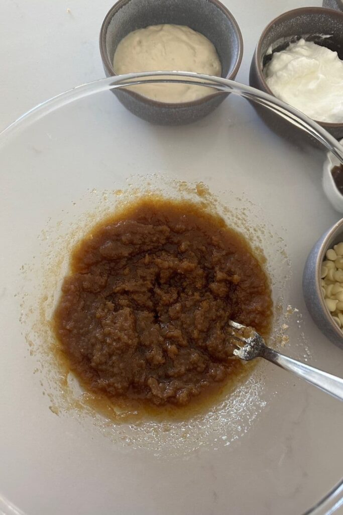 A glass bowl with brown sugar and melted butter mixed together. It looks a bit like lumpy caramel.