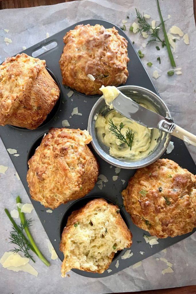 A tray of sourdough cheese muffins with a bowl of herbed butter.
