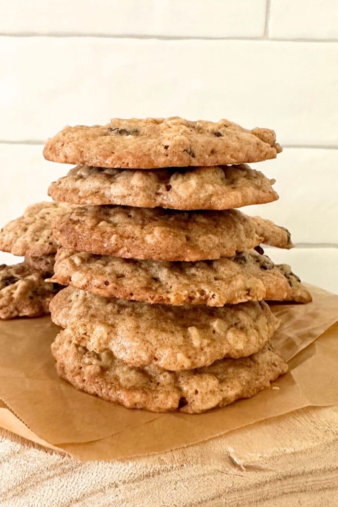 A stack of sourdough discard oatmeal raisin cookies sitting in front of a white tiled wall.