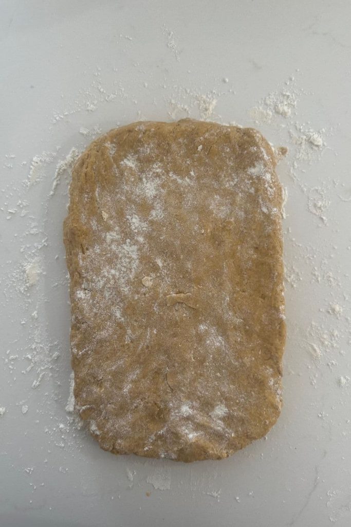 A rectangle of sourdough pumpkin scone dough that has been dusted lightly with flour.