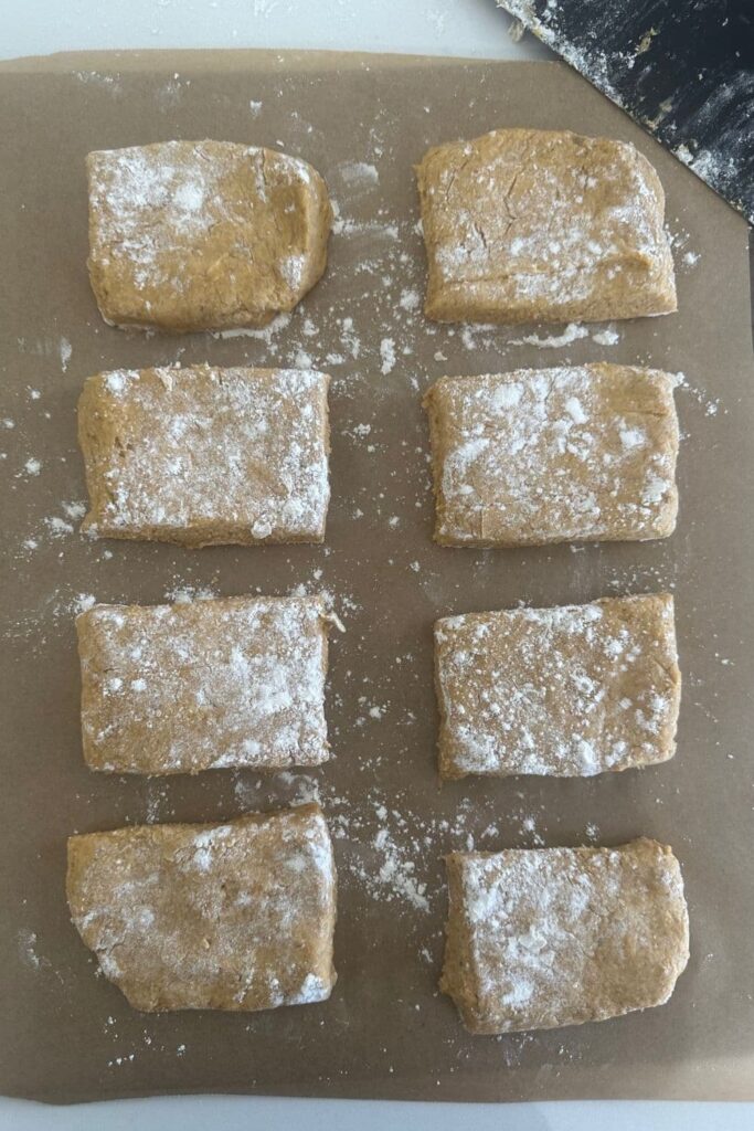 8 sourdough pumpkin scones dusted in flour sitting on a parchment paper lined baking tray.