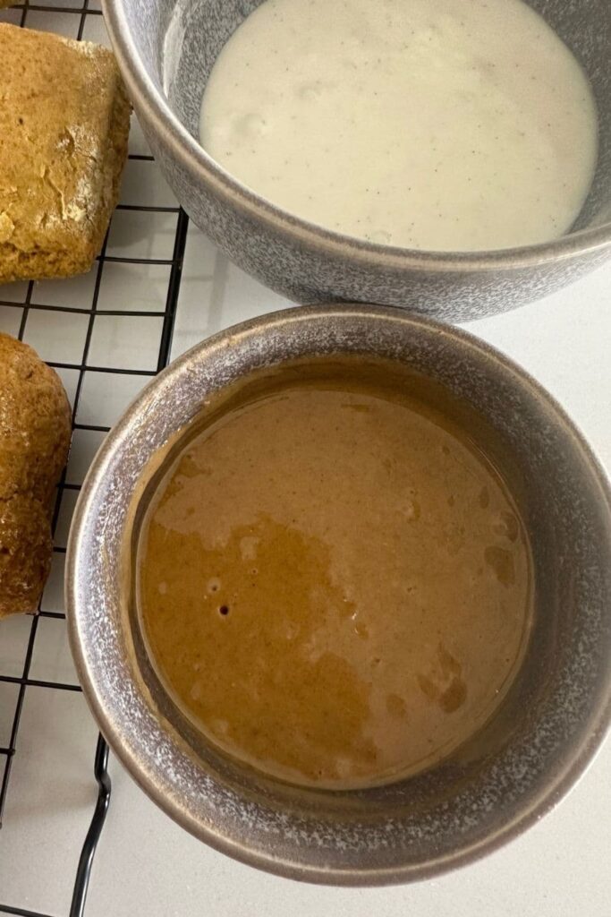 a grey bowl containing pumpkin spice glaze and another grey bowl containing a vanilla glaze.