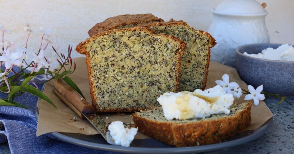 Seedy sourdough breakfast loaf served on a platter with whipped ricotta and honey.