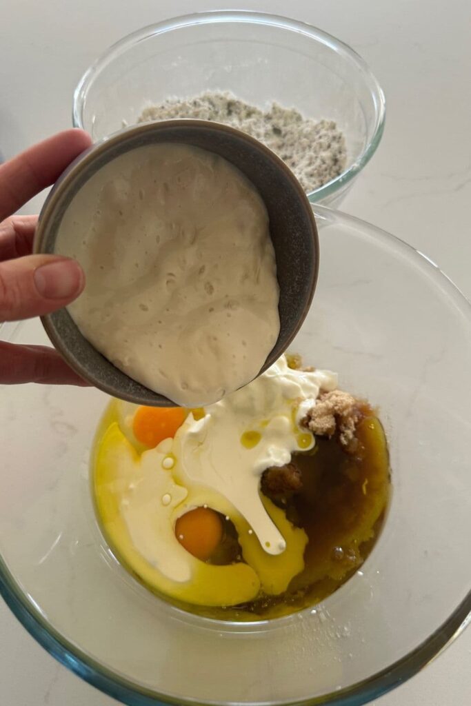 Pouring sourdough starter into the other wet ingredients for seedy sourdough breakfast loaf.