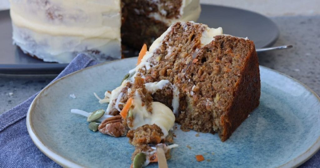 Slice of sourdough carrot cake placed on its side on a blue stoneware plate.