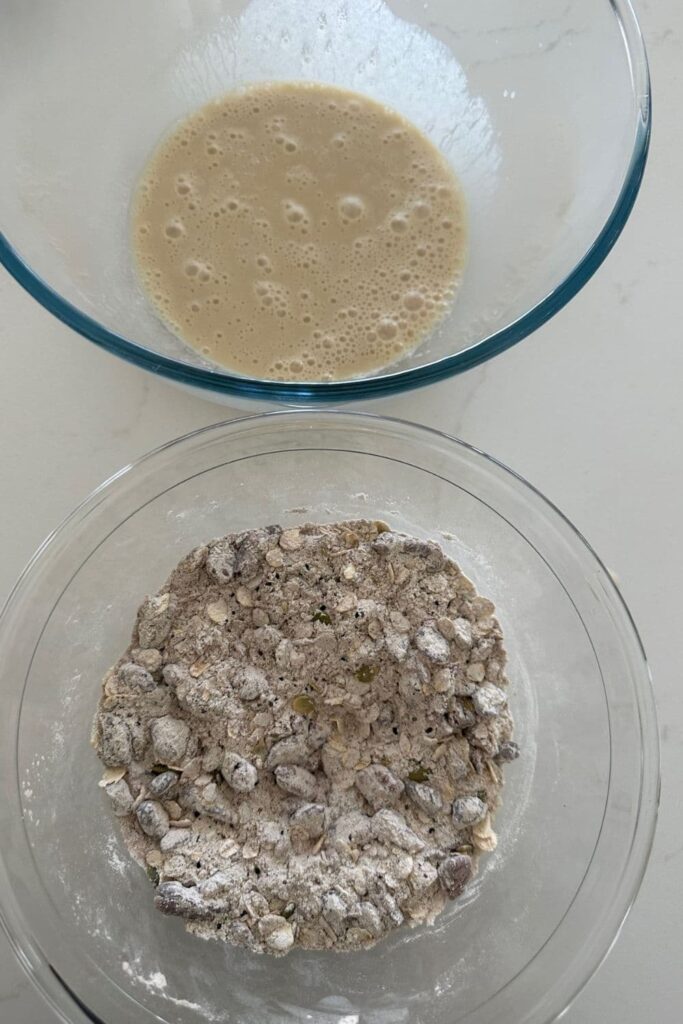 Bowl of dry ingredients for sourdough fruit and seed crackers sitting in front of the bowl of wet ingredients.