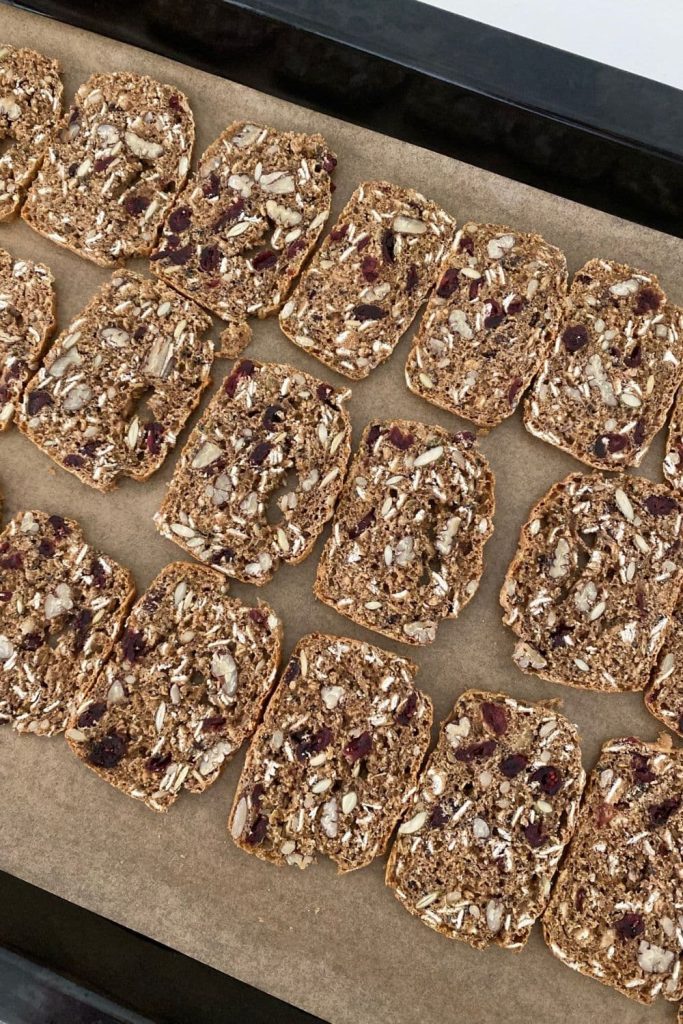 Sourdough fruit ad seed crackers that have been sliced and placed onto a baking tray ready for baking again.
