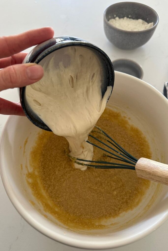 Sourdough starter being added to a bowl of ingredients when making sourdough quick bread recipes.