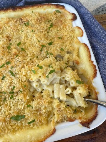 Sourdough mac and cheese baked in a white dish with breadcrumbs and parsley on top.