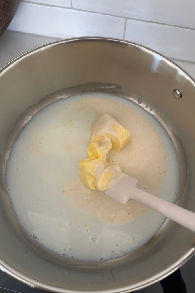 Butter, sourdough starter and milk used to make a roux in a large metal saucepan.