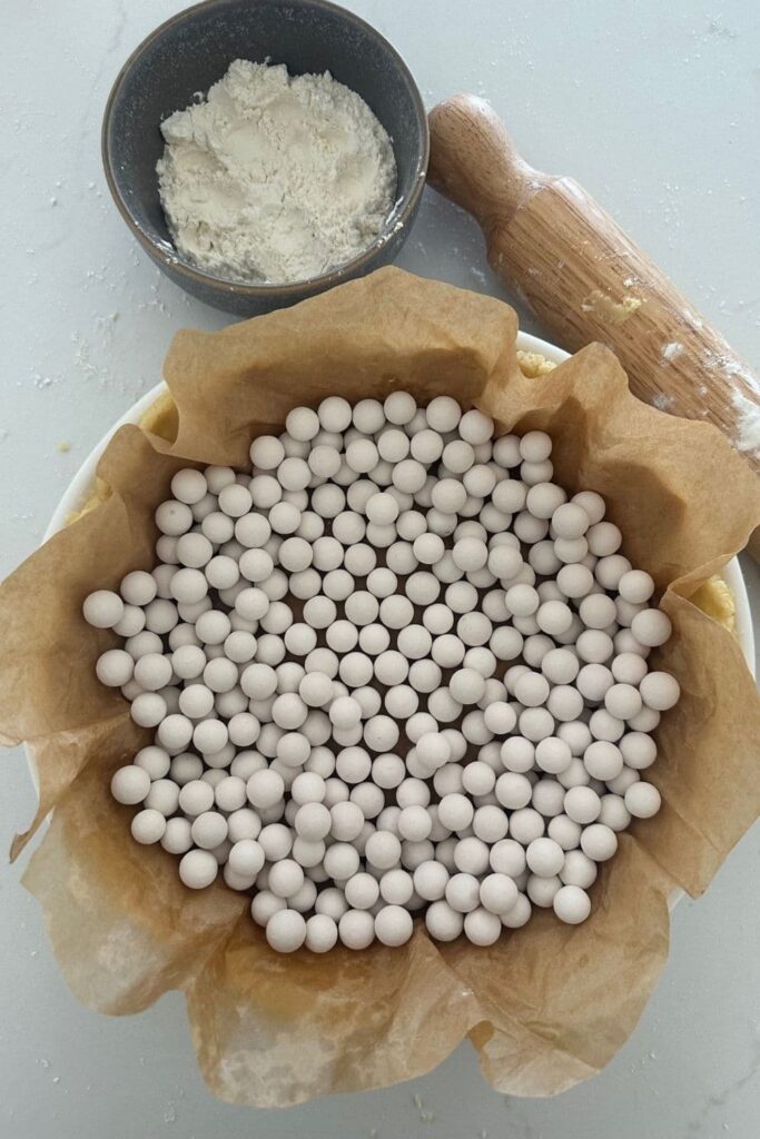 Sourdough pie crust with a sheet of parchment paper inside weighed down with pie weights.