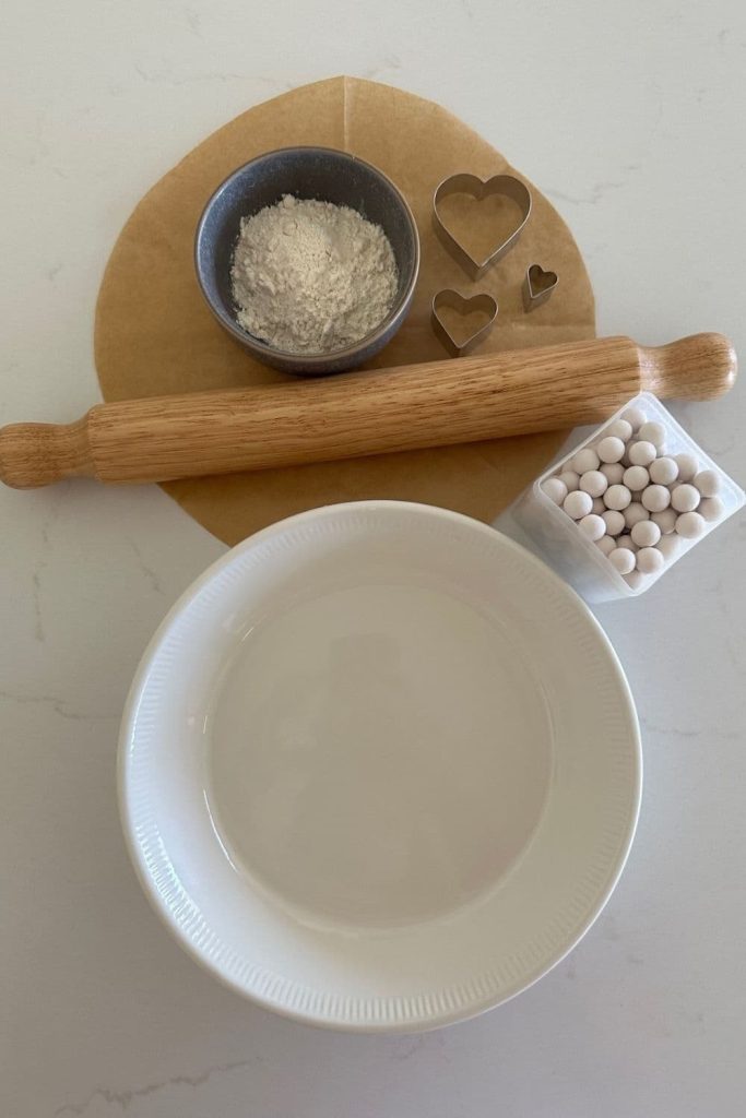 A photo of some of the equipment used to make sourdough pumpkin pie including a rolling pin, pie plate, pie weights and flour for dusting.