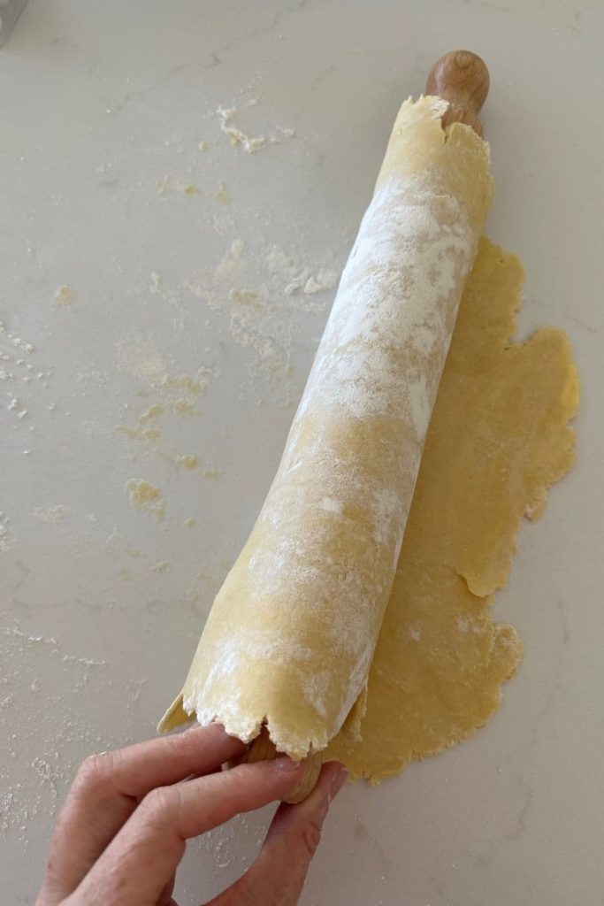 Sourdough pie crust rolled onto a rolling pin to make it easier to move it to the pie plate.
