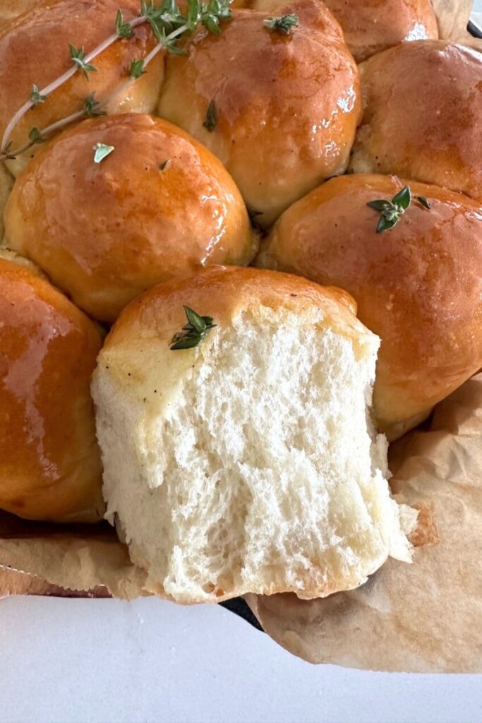 A photo showing a sourdough skillet roll that has been pulled apart from the rest to reveal the fluffy interior texture.