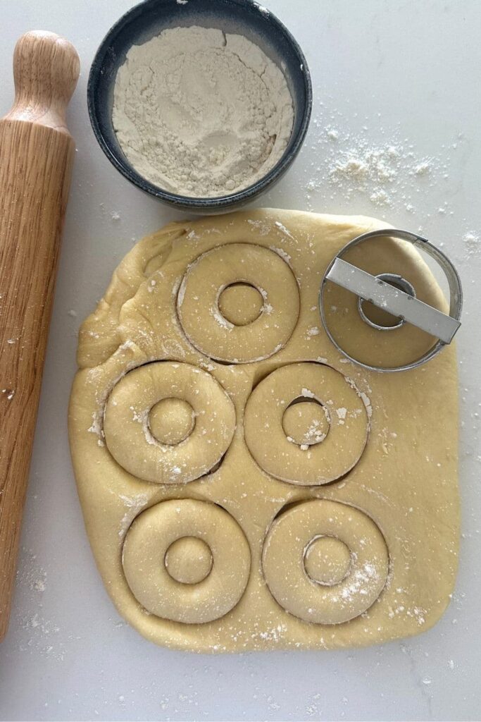 Cutting out sourdough donuts using a donut cutter.