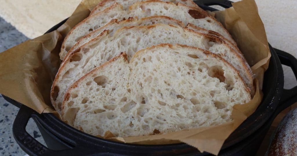 HIGH HYDRATION SOURDOUGH BREAD RECIPE - slices of high protein sourdough bread sitting in the lid of a Lodge Dutch Oven.