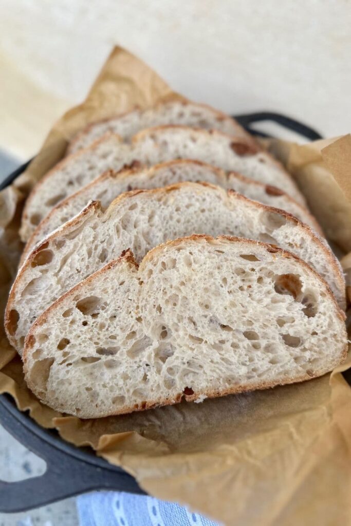 four slices of high hydration sourdough bread arranged in the lid of a Lodge Cast Iron Dutch Oven.