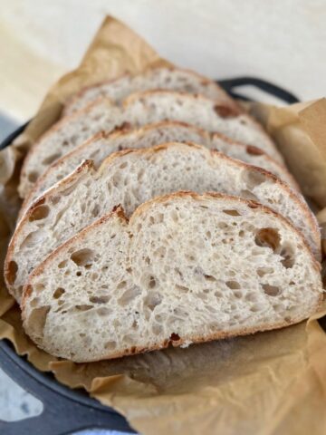 Photo showing what sourdough should look like inside - with four slices of open crumb sourdough sitting in the lid of a Lodge Cast Iron Dutch Oven.