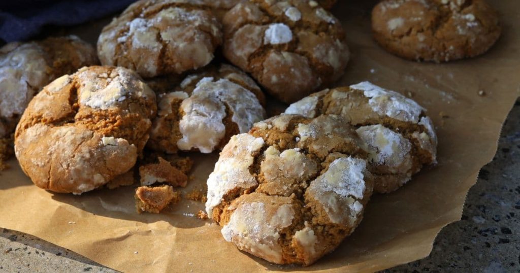 Sourdough gingerbread crinkle cookies coated in white powdered sugar that has crackled while they were in the oven.