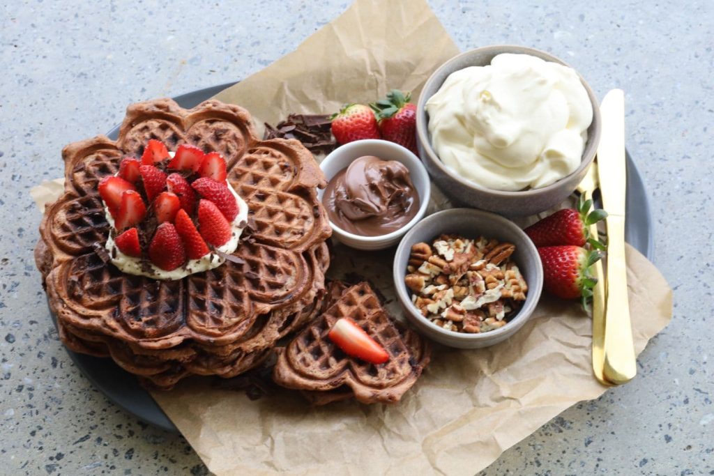 A Valentine's Day platter of sourdough chocolate waffles served with fresh strawberries, whipped cream, nutella and pecans.