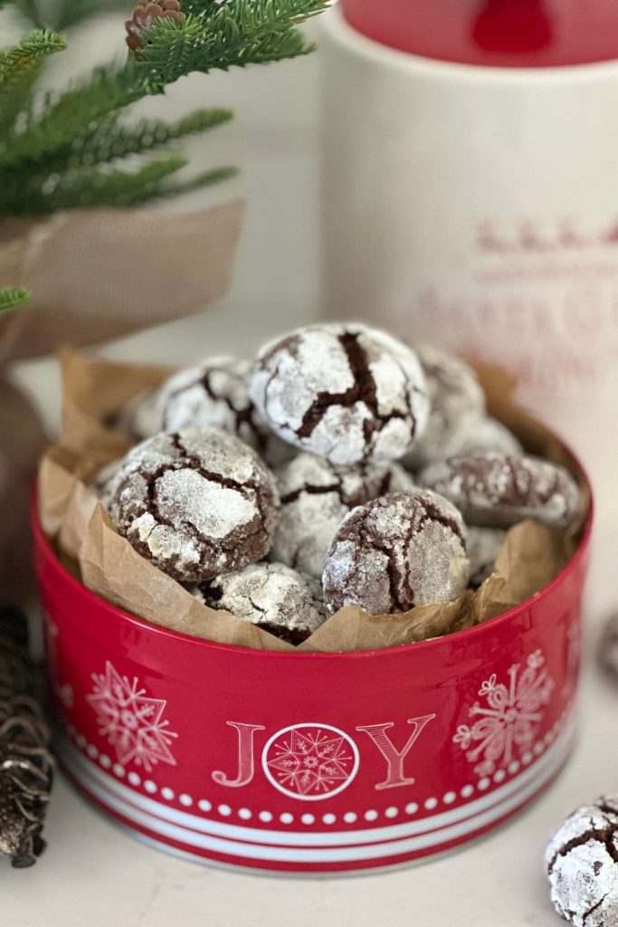 Sourdough chocolate crinkle cookies displayed in a red Christmas themed cookie tin.