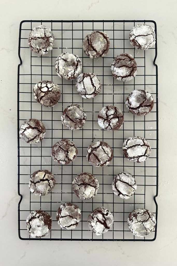 Sourdough chocolate crinkle cookies displayed on a black wire cooling rack.