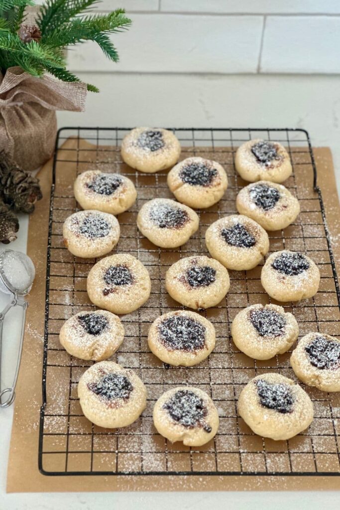 A black wire cooling rack with freshly baked sourdough fruit mince cookies laid out.