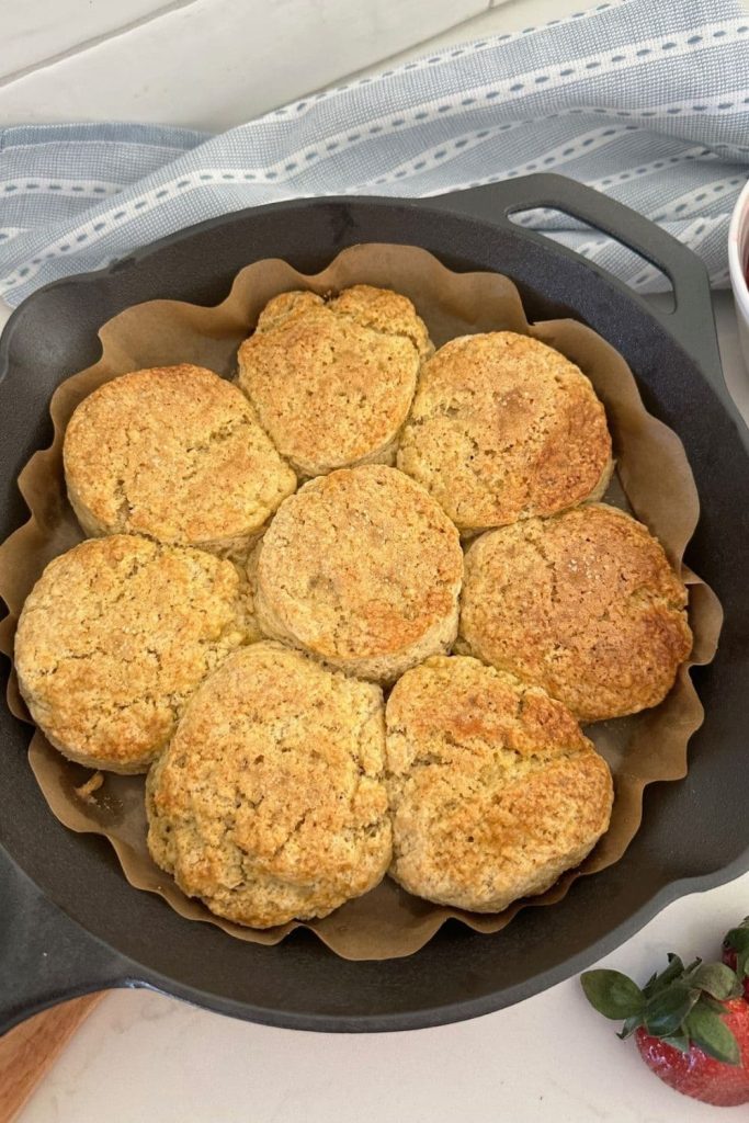 8 sourdough biscuits baked in a cast iron skillet. The biscuits have been topped with granulated sugar to give them a crunchy topping.