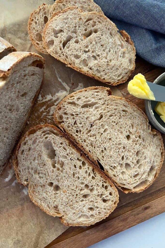 Slices of sourdough bread sitting next to a dish of butter.